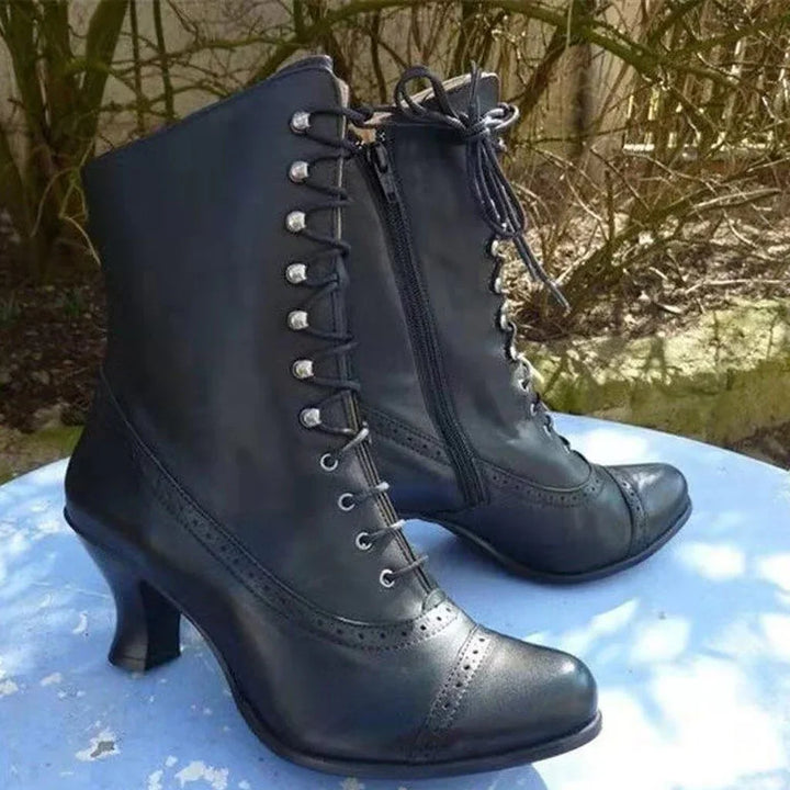 Black leather vintage lace-up heeled ankle boots with side zipper on blue surface outdoors