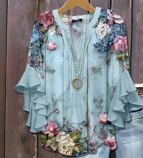 Light blue floral blouse with ruffled bell sleeves and pearl necklace on wooden hanger
