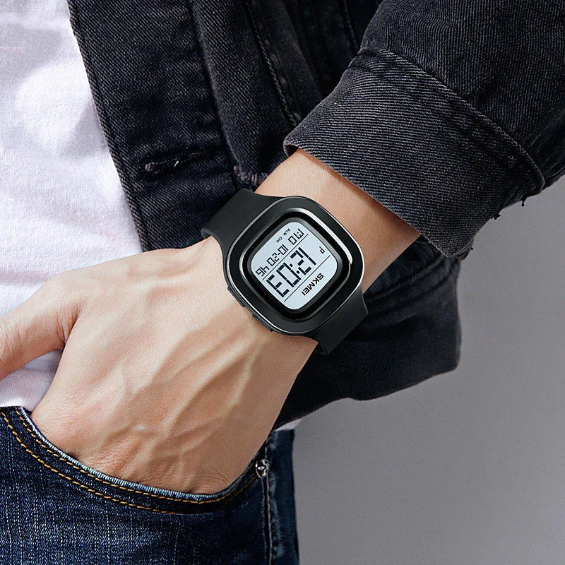Person wearing black digital sports watch with square face and rubber strap on wrist