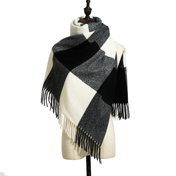 Black, white, and gray checkered wool scarf with fringes displayed on dress form