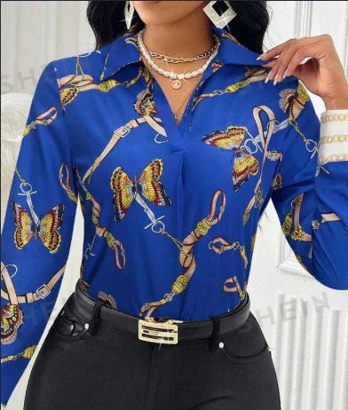 Woman wearing blue blouse with butterfly and chain print, paired with black pants and gold accessories