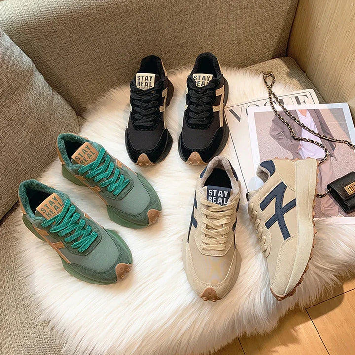 Three pairs of Stay Real branded sneakers in black, green, and beige on white fur with Vogue magazine and black purse
