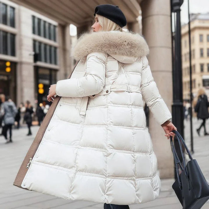 Woman in white long puffer coat with fur hood and black beret walking in city street with black handbag