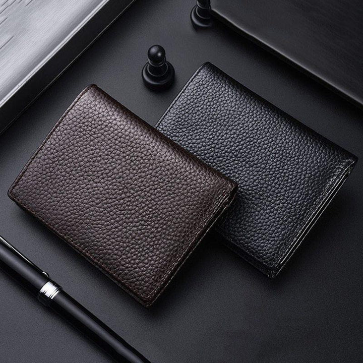 Two textured leather wallets, one brown and one black, placed on a black surface with a pen and chess pawns