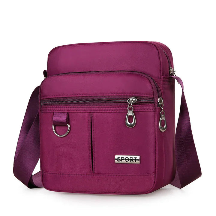 Compact purple crossbody sport bag with multiple zippered compartments and adjustable strap