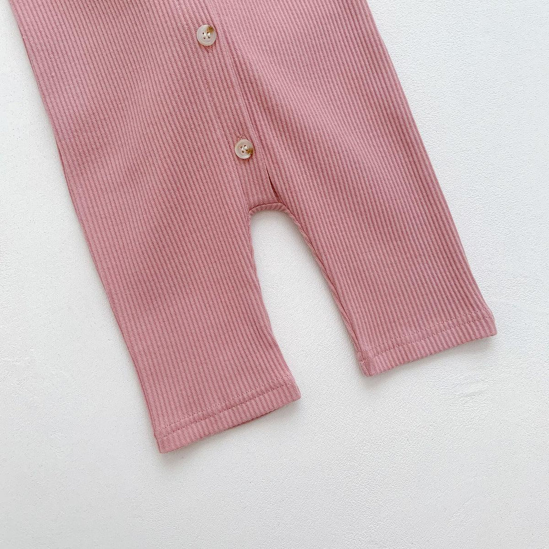 Close-up of pink ribbed fabric baby romper legs with two beige buttons on white background