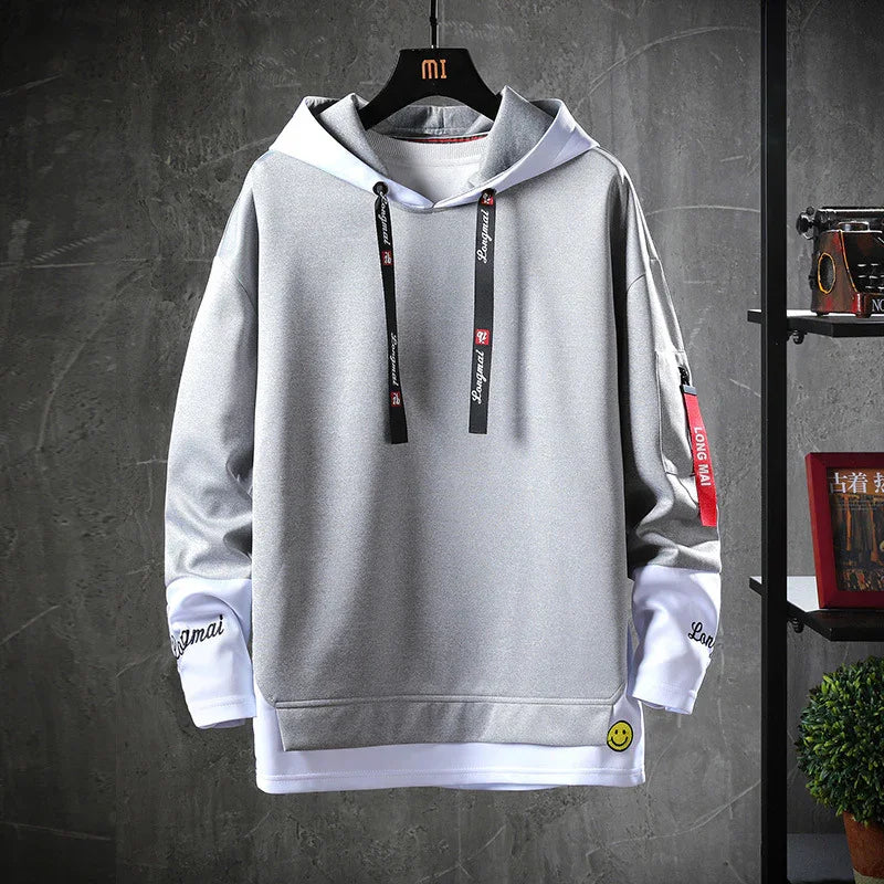 Stylish gray and white hoodie with black drawstrings, red sleeve tag, and smiley face patch