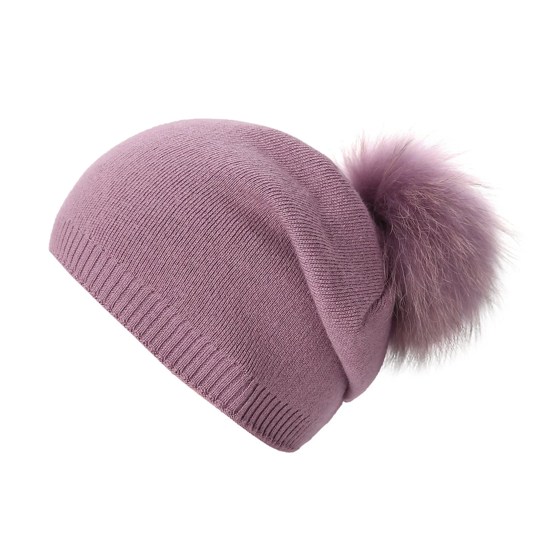 Mauve knitted beanie hat with a large fluffy pom pom on white background