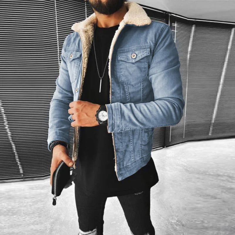 Man wearing blue denim jacket with white shearling collar, black shirt, ripped black jeans, holding black wallet