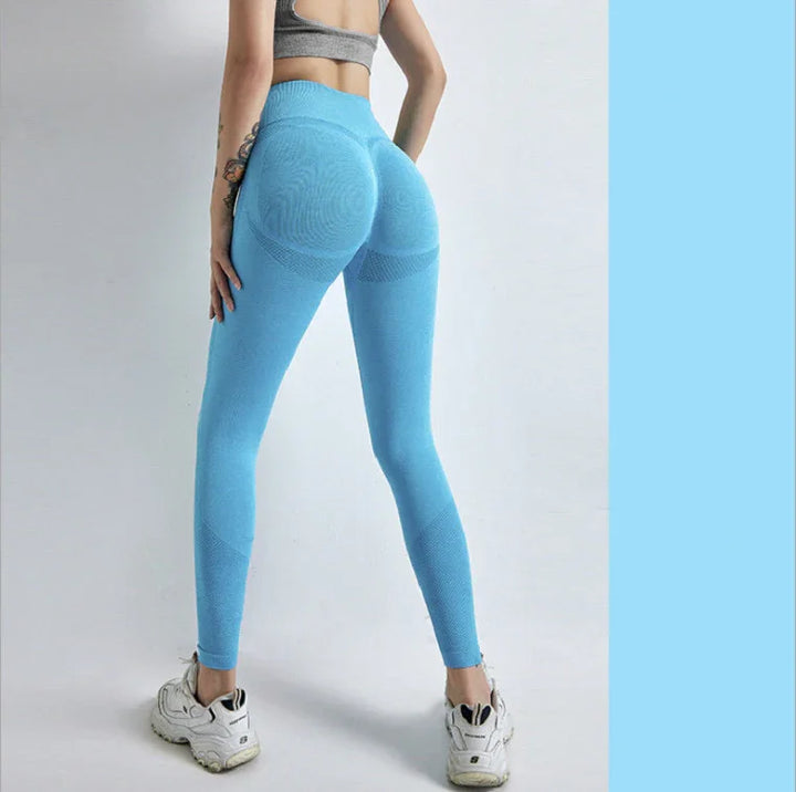 Woman wearing bright blue seamless leggings and white sneakers against plain background
