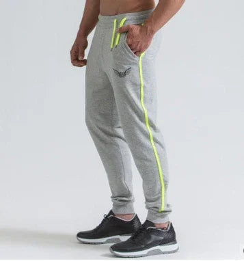 Gray men's jogger pants with neon yellow stripe and drawstring, paired with black athletic shoes