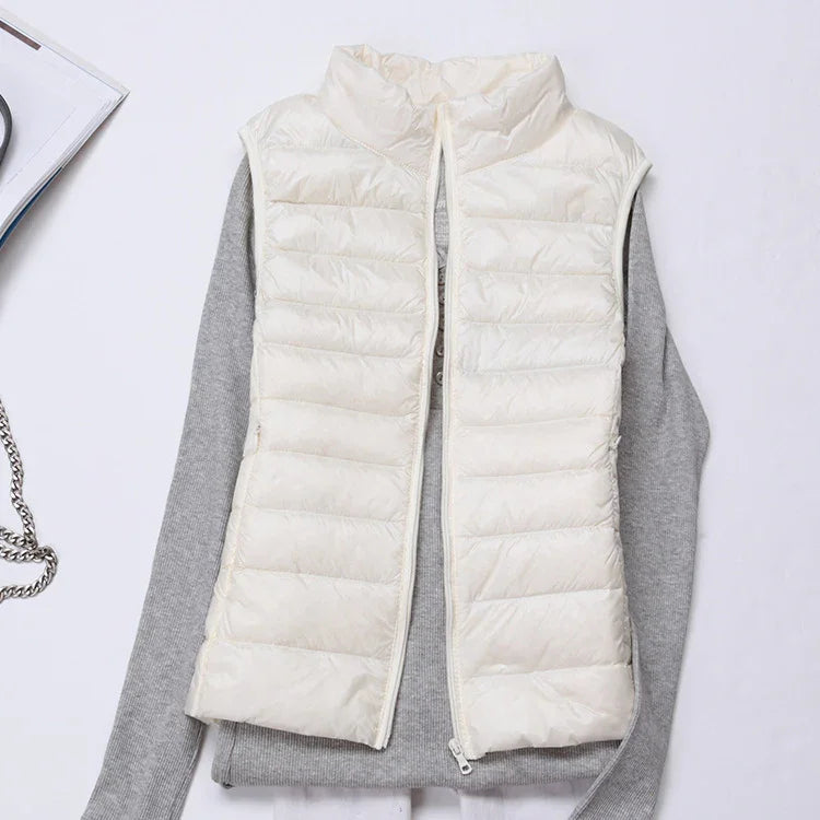 white quilted sleeveless puffer vest over gray long-sleeve shirt on white background