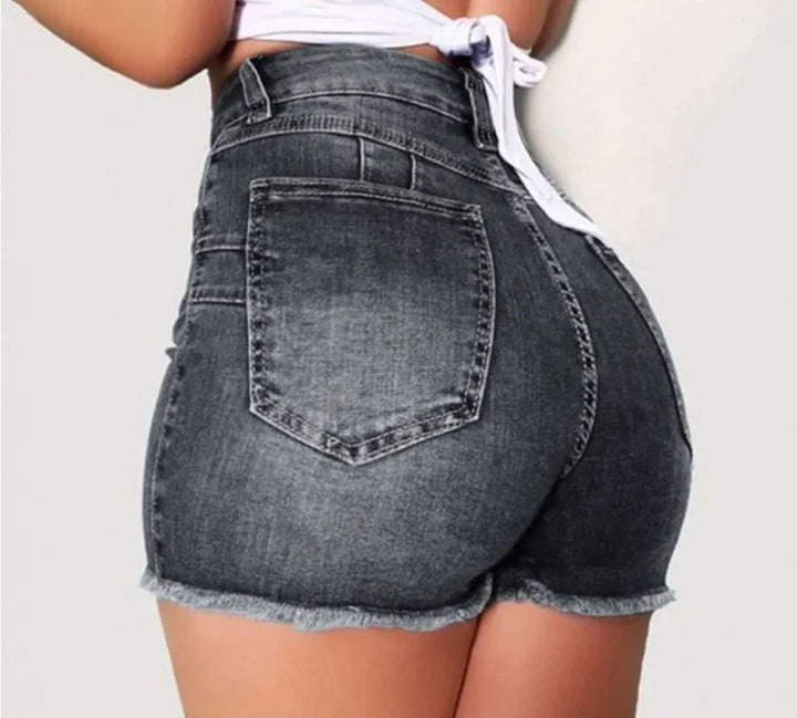 Back view of woman wearing high-waisted black denim shorts with frayed hems and a tied white crop top