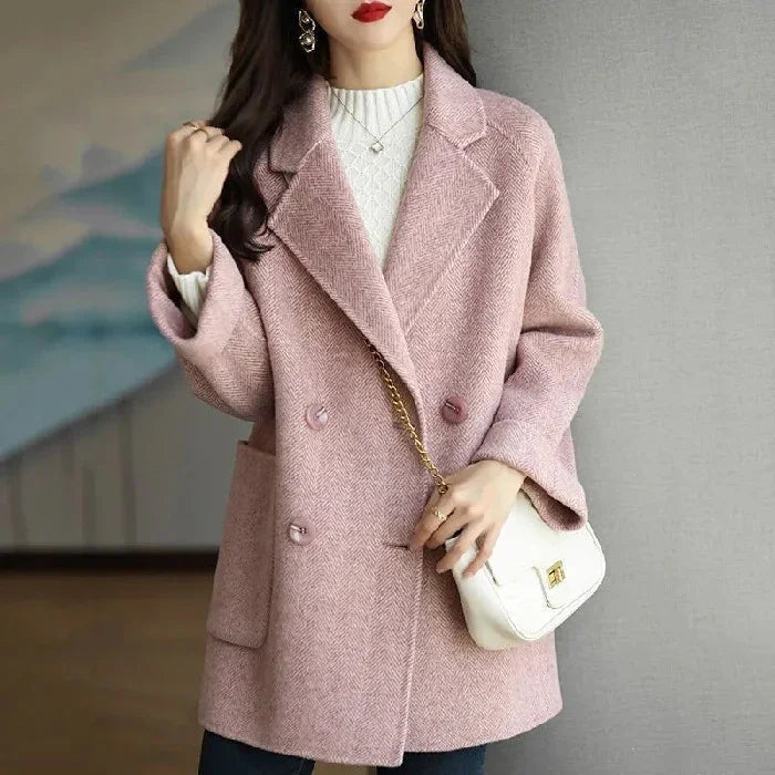 Woman wearing a pink double-breasted wool coat with side pockets and white handbag