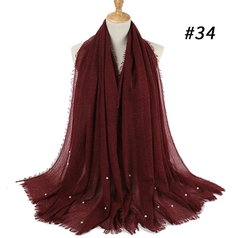 Burgundy cozy scarf with pearl accents displayed on a mannequin, soft textured fabric