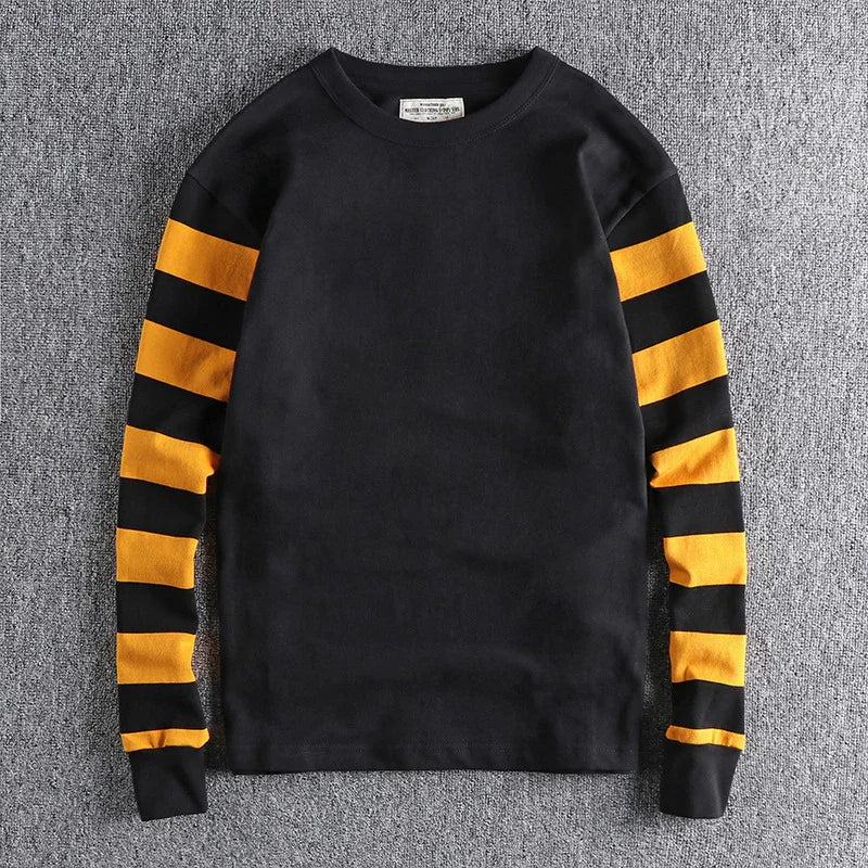 Black long-sleeve sweatshirt with bold yellow and black horizontal stripes on sleeves on gray background