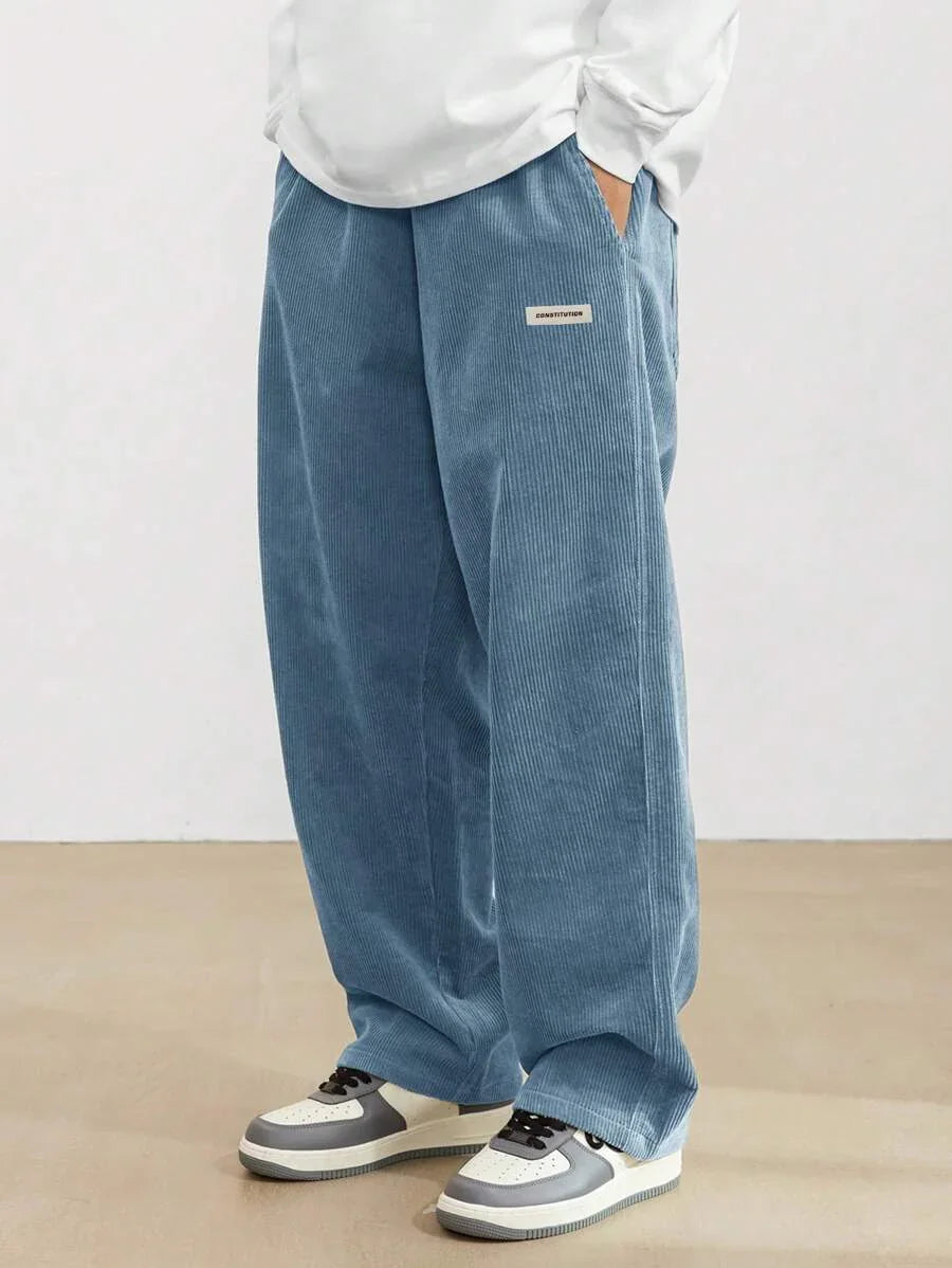 Blue corduroy wide-leg pants with a small label, paired with white and gray sneakers