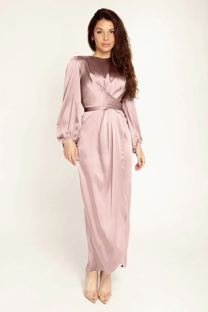 Woman wearing a mauve satin long-sleeve wrap dress with puffed sleeves and clear heels