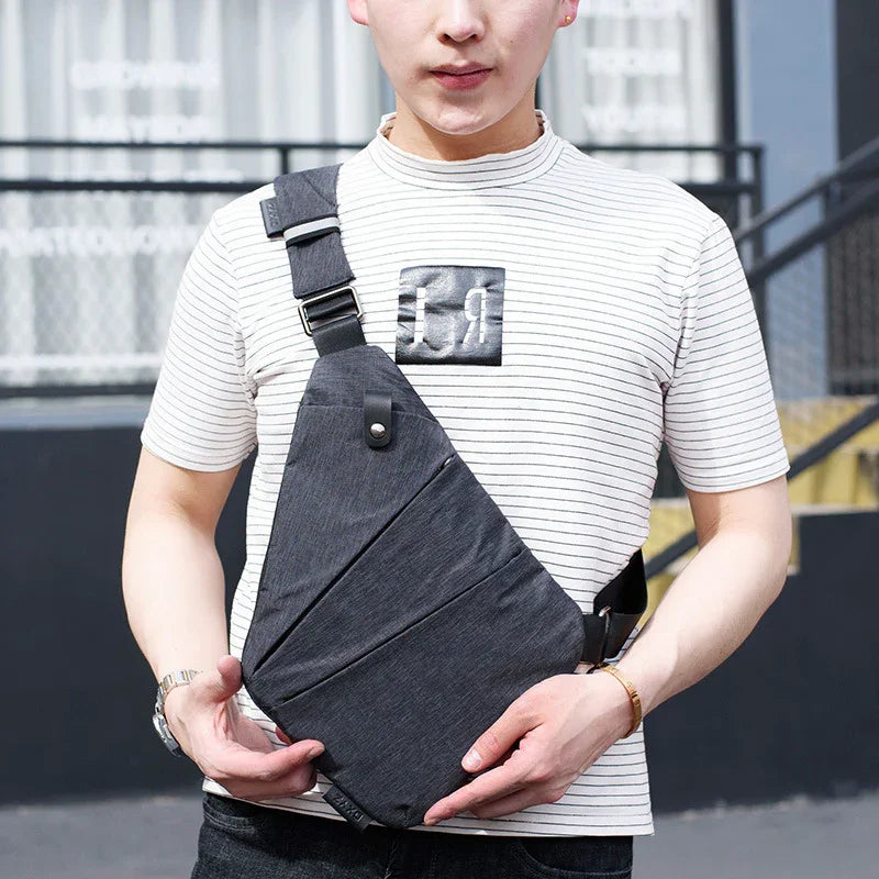 Man wearing a black crossbody sling bag and white striped t-shirt outdoors
