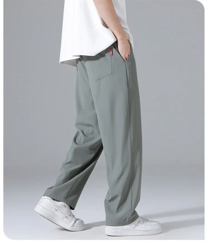 Side view of person wearing loose gray pants with back pocket and white sneakers