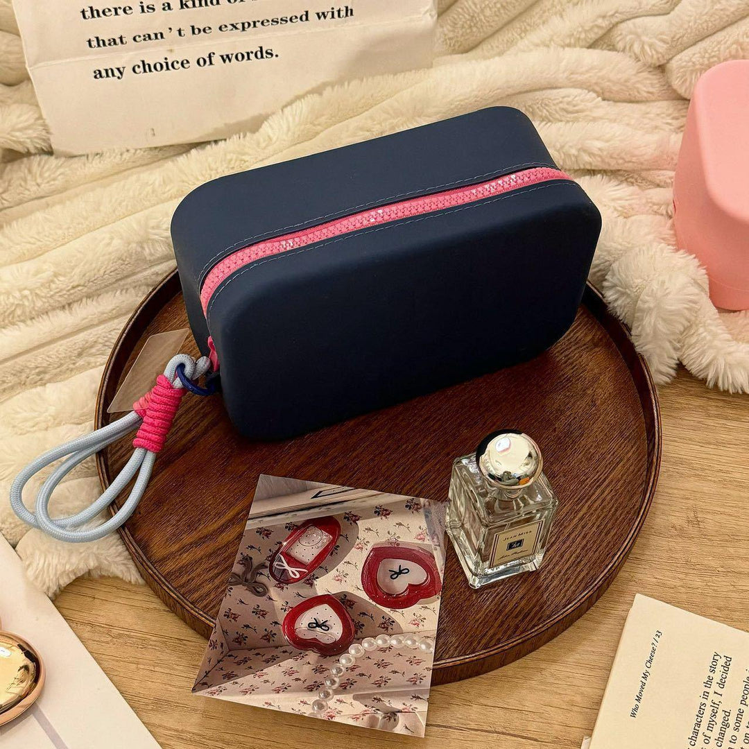 Black cosmetic bag with pink zipper on round wooden tray with Jo Malone perfume and decorative cards