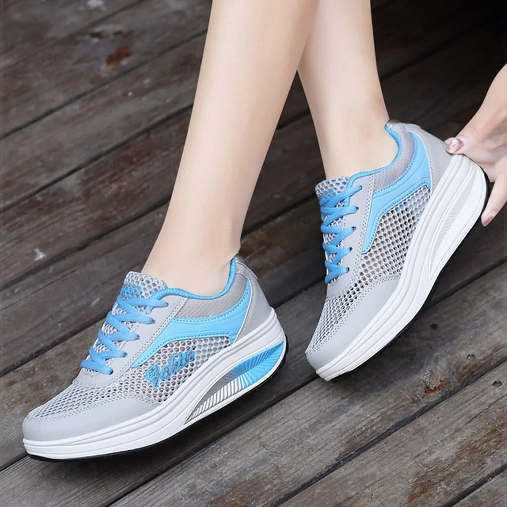 Light gray and blue breathable mesh sneakers with cushioned soles on wooden floor