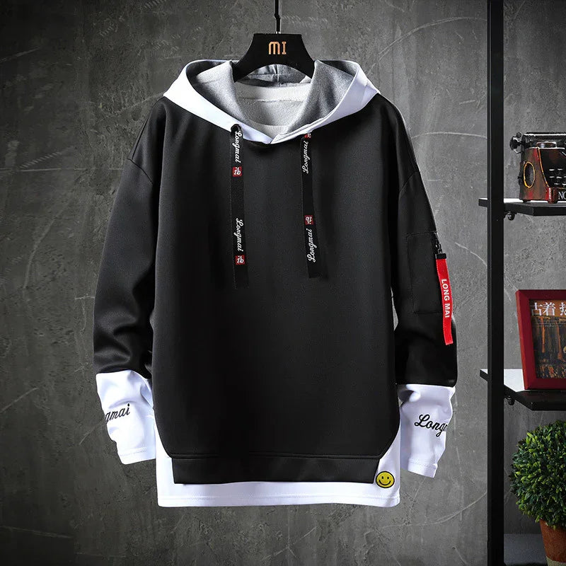 Black and white layered hoodie with grey hood, red tag on sleeve, and smiley face patch on hem