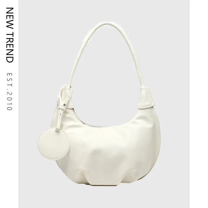 Elegant white crescent handbag with round tag and single handle on light background