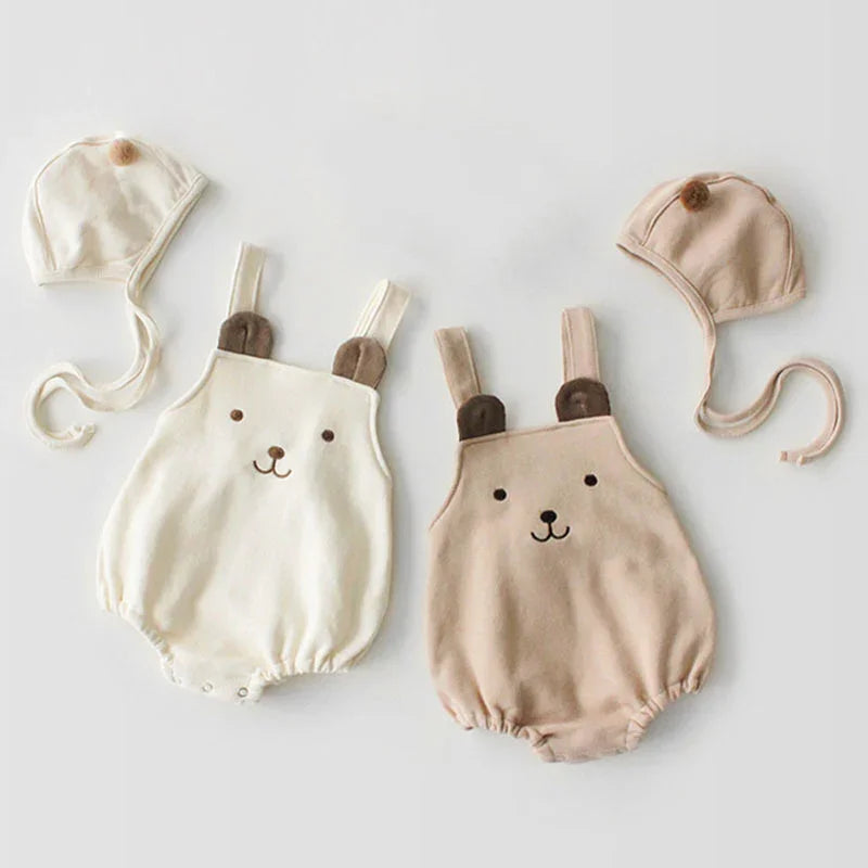 Two baby rompers with cute bear face designs and matching hats with pom-poms in cream and beige colors