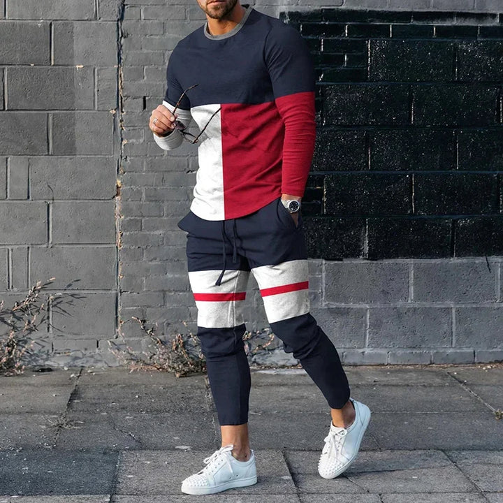 Man wearing stylish color-blocked navy, red, and white tracksuit with white sneakers on urban street
