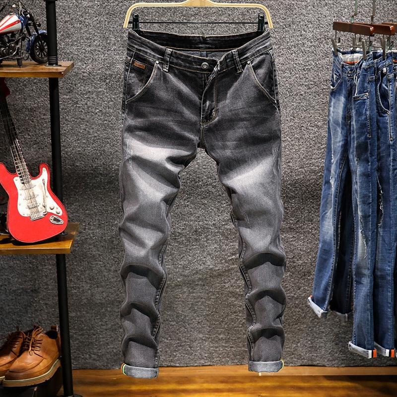 Gray distressed slim fit jeans hanging on wooden hanger in modern retail display with denim jeans and shoes