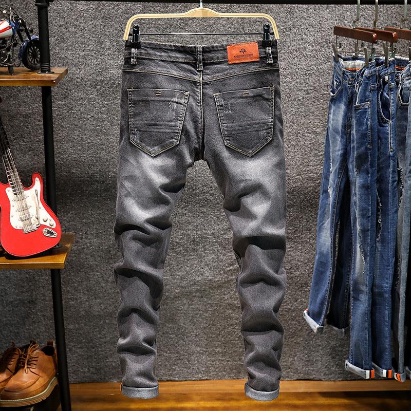 Back view of faded black slim-fit jeans hanging on wooden hanger in clothing store