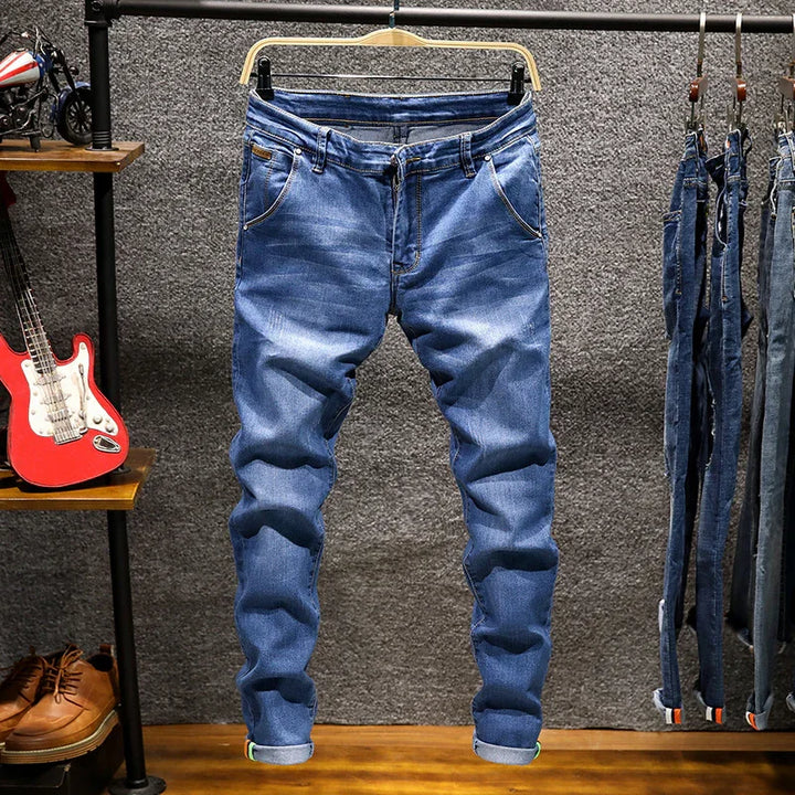 Blue denim jeans hanging on rack in a casual retail setting with guitars and shoes nearby