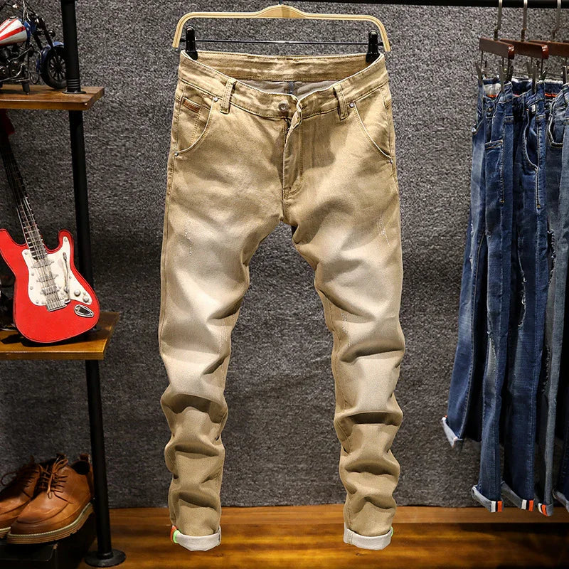 Beige slim-fit men's jeans hanging on wooden hanger in retail store with blue jeans and accessories