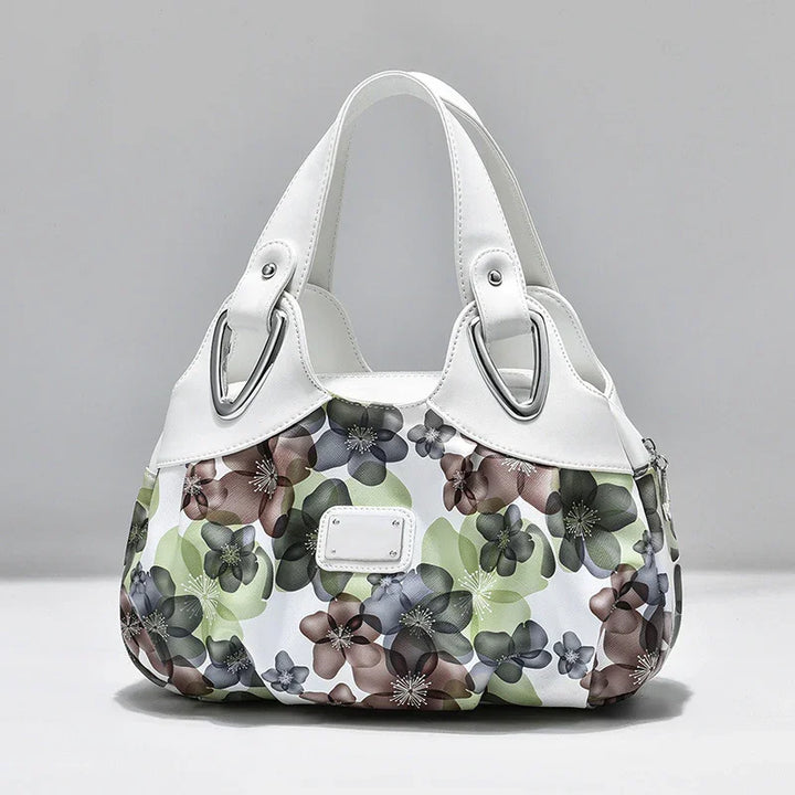 White handbag with multicolor floral print and silver hardware on gray background