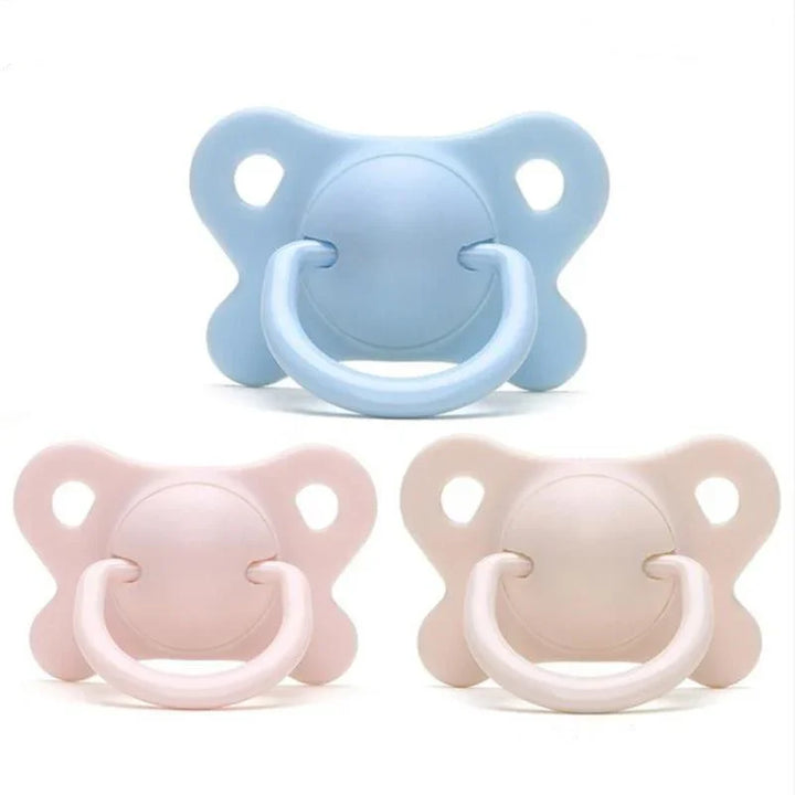 Set of three pastel baby pacifiers in blue, pink, and beige colors with butterfly-shaped shields