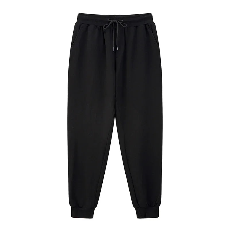 Black casual jogger pants with elastic waistband, drawstring, side pockets, and cuffed ankles
