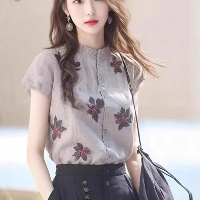 Woman wearing light grey floral embroidered blouse and high-waisted black skirt with buttons