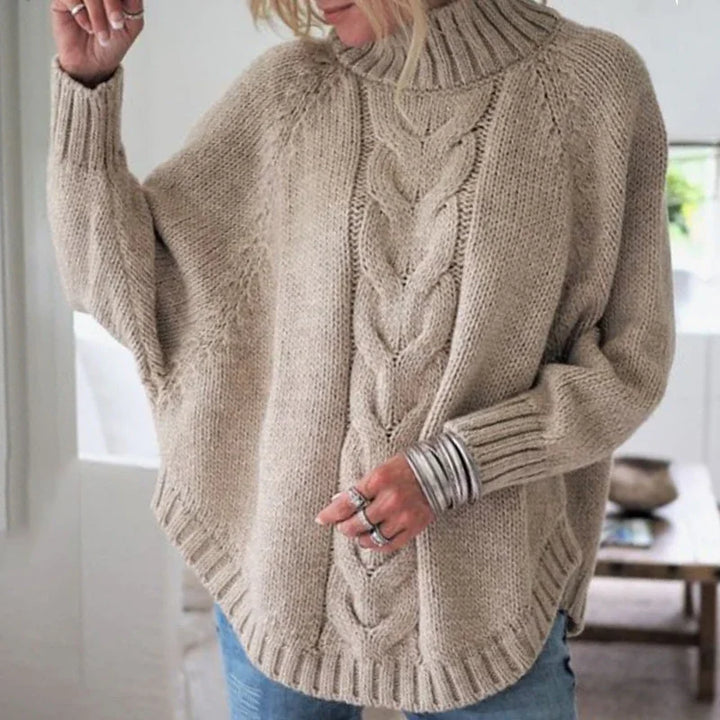 Woman wearing beige chunky knit turtleneck sweater with cable pattern and loose sleeves