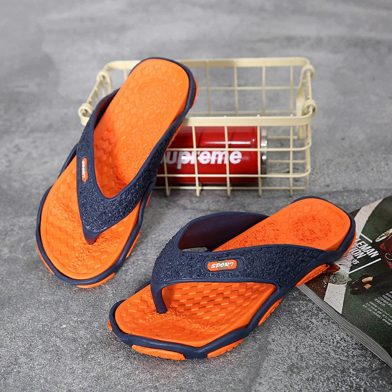 Orange and black sporty flip-flops on gray floor with red Supreme can and magazine