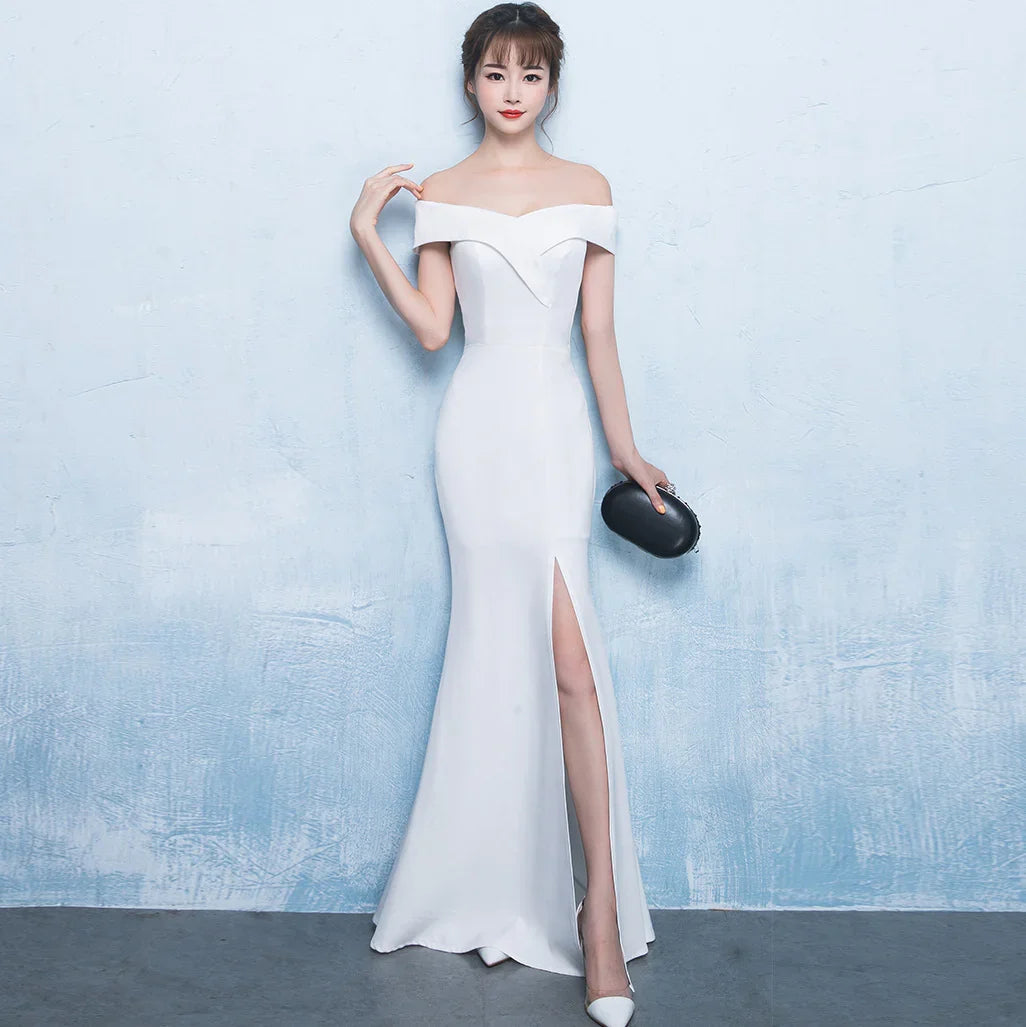 Elegant woman in off-shoulder white evening gown with thigh slit holding black clutch