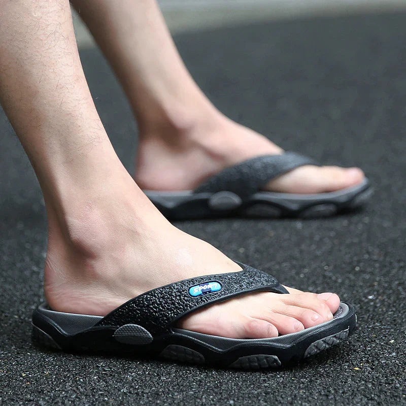 Close-up of feet wearing black sport flip-flops on textured asphalt surface