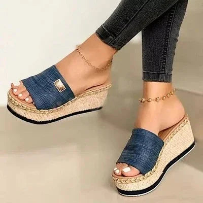 Woman wearing denim platform wedge sandals with woven espadrille sole and ankle bracelets