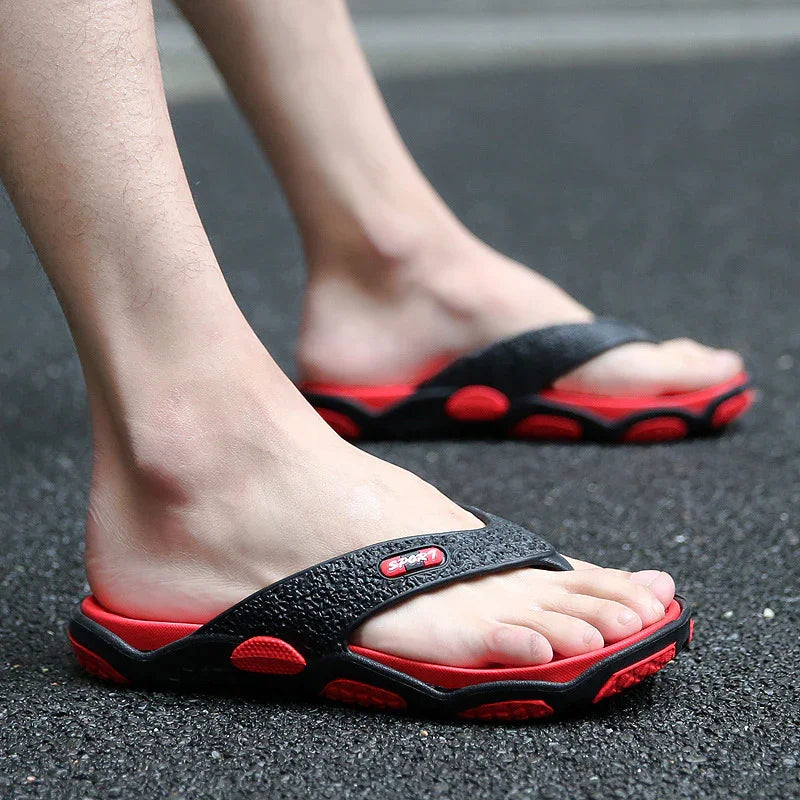 Feet wearing black and red sporty flip-flops on asphalt ground