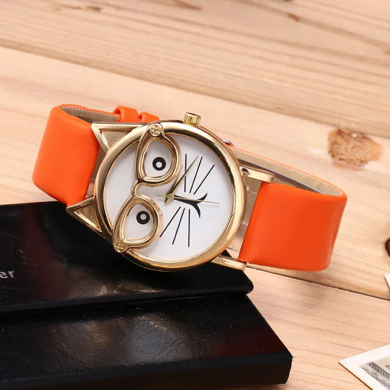 Close-up of a cute cat-face wristwatch with orange strap and gold-rimmed glasses design on wooden surface