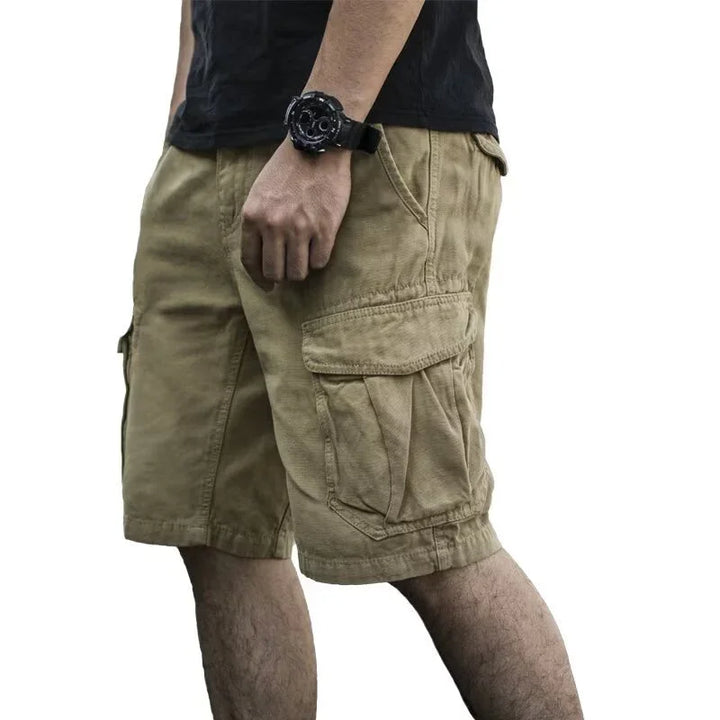 Man wearing khaki cargo shorts and black watch with a black t-shirt on white background