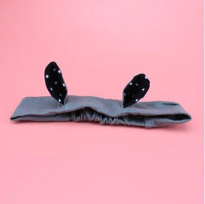 Gray fabric headband with black bunny ears featuring white star patterns on pink background