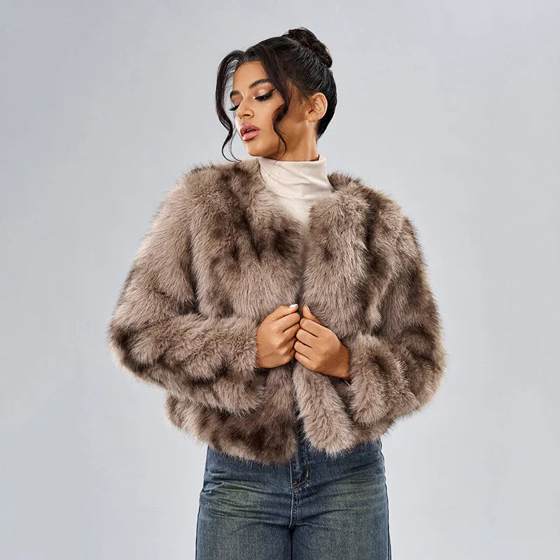 Woman wearing a brown faux fur jacket over a white turtleneck and blue jeans against gray background