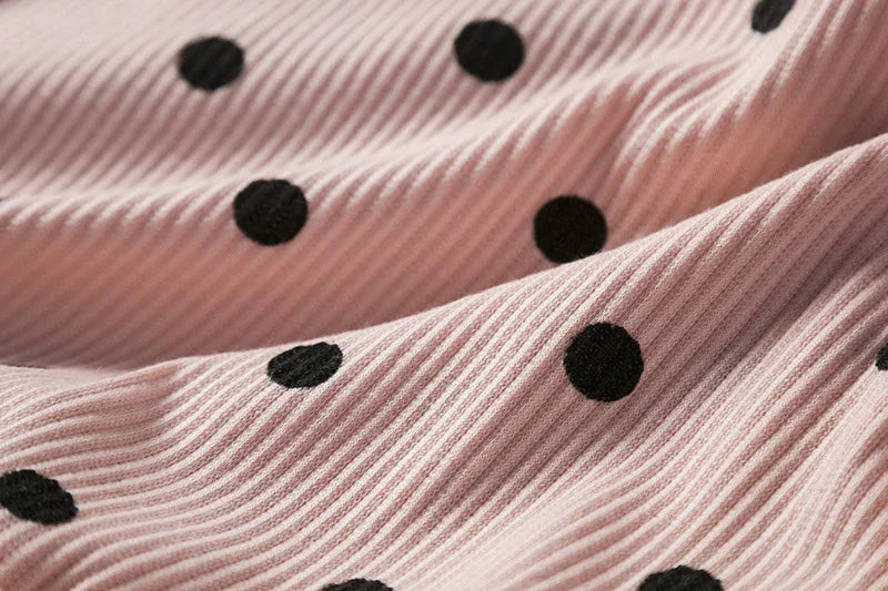 Pink ribbed fabric with black polka dot pattern, textured textile close-up