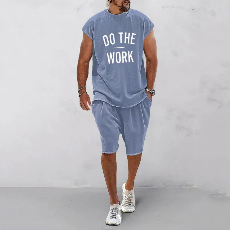 Man wearing blue sleeveless shirt with 'DO THE WORK' text and matching shorts with white sneakers